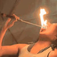 A person performs a fire-eating act, tilting their head back with their mouth open as…
